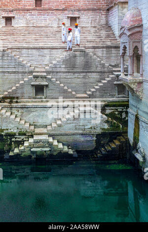 Tre uomini a piedi verso il basso i passaggi alla stepwell Toorji Ka Jhalra in Jodhpur, Rajasthan, India Foto Stock