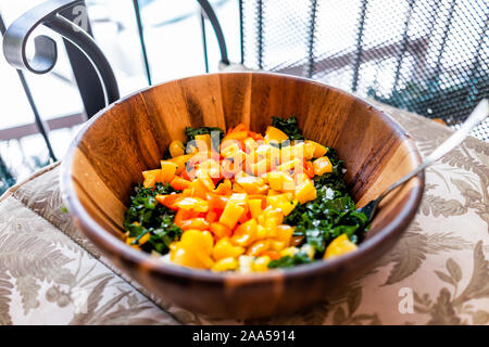 Primo piano di una grande insalatiera di legno con un trito di cavolo verde e giallo arancio peperoni vegano come il pranzo o la cena sul balcone sedia Foto Stock