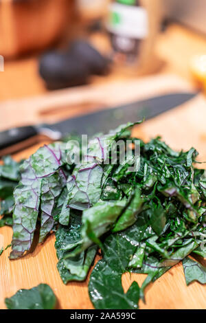 Tagliere con un trito di verde rosso foglie di cavolo in cucina verdure per pasto sano la cottura di preparazione e il coltello in background Foto Stock