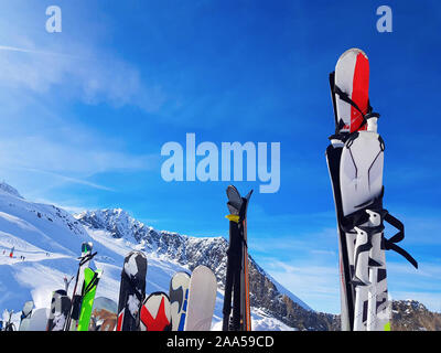Immagine di multi-colore di sci e snowboard nella neve in inverno resort nel pomeriggio. Sfondo sfocato. Foto Stock