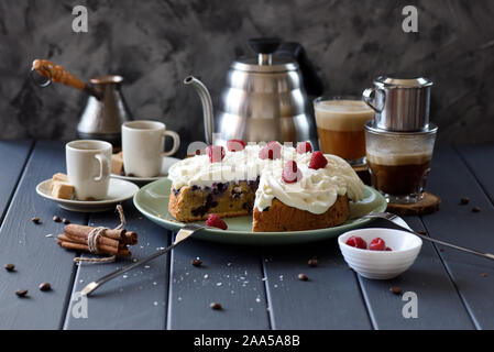 Una sana a basso contenuto di zucchero torta di frutta con crema di cocco rose e lamponi servita con caffè nero su sfondo scuro copia spazio. Ancora vita con naturale Foto Stock