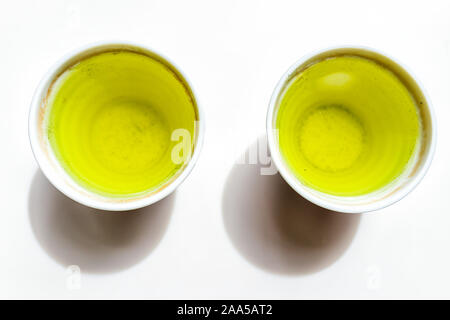 Lato superiore piatto vista laici verso il basso delle piccole due tazze riempite con giapponese giallo vivace Sencha tè genmaicha colore per la prima colazione o la cerimonia Foto Stock