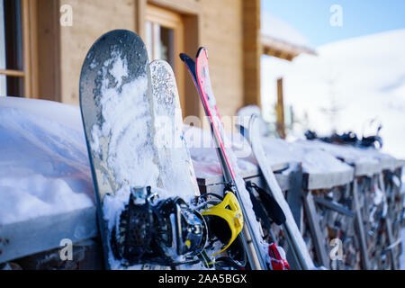 Immagine di multi-colore di sci e snowboard nella neve in inverno resort nel pomeriggio. Sfondo sfocato. Foto Stock