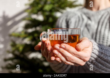 Tazza da tè nella donna la mano con albero di Natale in background. Concetto di Natale in casa umore Foto Stock