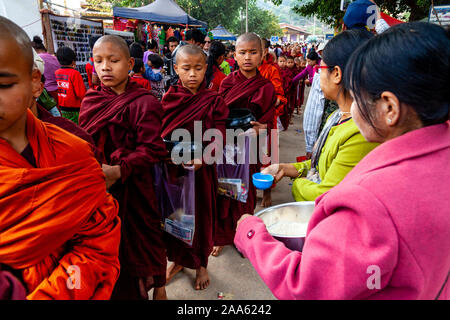 Il debuttante monaci a piedi giù per la strada principale di Pindaya Cerca Alms durante la grotta di Pindaya Festival, Pindaya, Stato Shan, Myanmar. Foto Stock