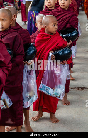 Il debuttante monaci a piedi giù per la strada principale di Pindaya Cerca Alms durante la grotta di Pindaya Festival, Pindaya, Stato Shan, Myanmar. Foto Stock