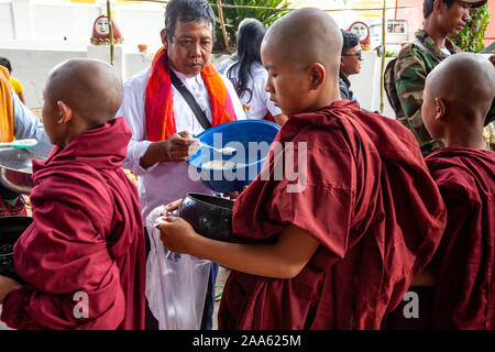 Il debuttante monaci a piedi giù per la strada principale di Pindaya Cerca Alms durante la grotta di Pindaya Festival, Pindaya, Stato Shan, Myanmar. Foto Stock