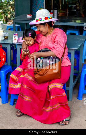 Una nonna birmana guarda con Pride come sua nipote usa UN cellulare (cellulare), Pindaya, Shan state, Myanmar. Foto Stock