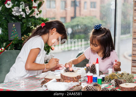 Due piccole sorelle divertirsi mentre si effettua il Natale Presepi artigianali con a casa - Famiglia Reale Foto Stock