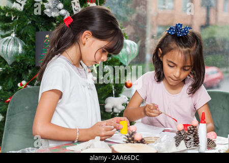 Due piccole sorelle divertirsi mentre si effettua il Natale Presepi artigianali con a casa - Famiglia Reale Foto Stock
