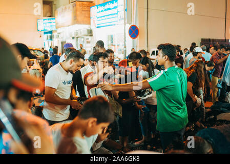 Un venditore ambulante vende un paio di scarpe una sera in Haraj Souq - un vivace mercato delle pulci a Doha, in Qatar Foto Stock