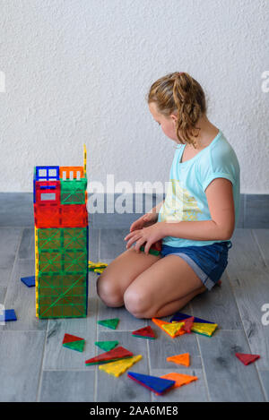 Bella ragazza adolescente giocando con un sacco di colorati di materia plastica in blocchi costruttore e costruisce la casa. Foto Stock