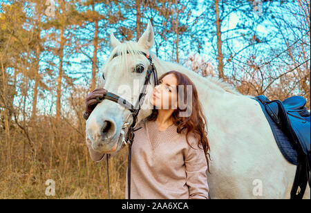 Ragazza in sella ad un cavallo bianco nel bosco Foto Stock