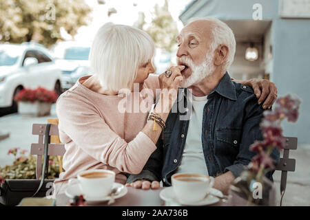 Positivo senior bella donna alimentando il marito Foto Stock