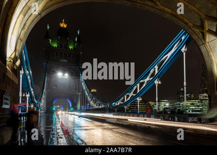 London, England, Regno Unito - 15 Novembre 2019: il traffico si sfoca in percorsi di luce su una notte piovosa il Tower Bridge di Londra. Foto Stock