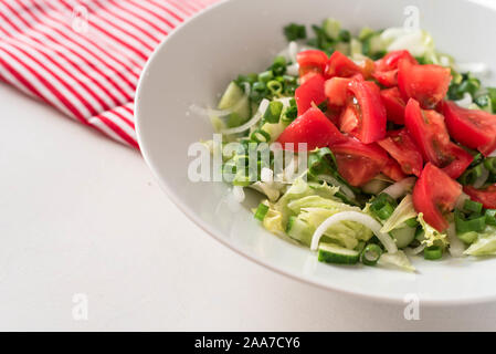 Insalata georgiano Pomodori Cetrioli e cetriolini, cipolle, sul tavolo bianco rosso igienico Foto Stock