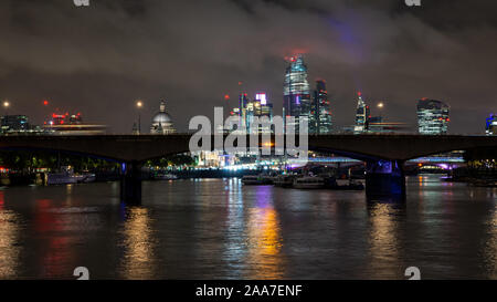 London, England, Regno Unito - 14 Ottobre 2019: Autobus formano una sfocatura su Waterloo Bridge di notte, con la City of London skyline dietro. Foto Stock
