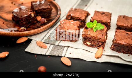 In casa, brownie al cioccolato con nocciole e mandorle su sfondo nero Foto Stock