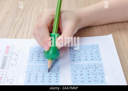 Bambino la mano con strumento di scrittura per aiutare da imperfetta tenuta della matita, homewortk, matematica Foto Stock