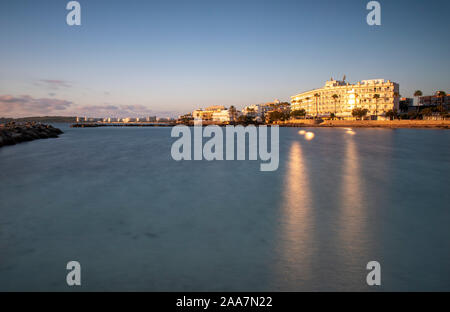 Cala Bona guardando verso Cala Millor e il Protur Alicia Hotel a sunrise. Bella riflessioni su il sole in acqua che è calma e setoso sm Foto Stock