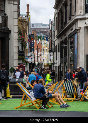 London, England, Regno Unito - 22 Settembre 2019: gli amanti dello shopping a piedi lungo Carnaby Street e sedersi sulle sedie a sdraio sul Regents Street a Londra durante la Giornata senza automobili eve Foto Stock