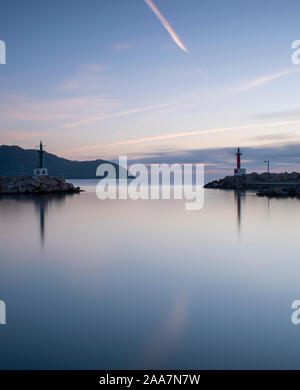 Sunrise Cala Bona Harbour Maiorca con lisce come la seta mare piatto e bellissimi riflessi nell'acqua. Foto Stock