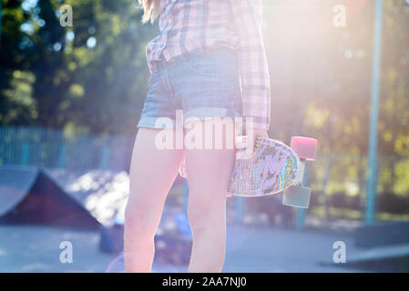 Femmina Skater corse su skateboard a skate park rampa. Giovane donna praticare lo skateboard all'aperto a skate park. Foto Stock