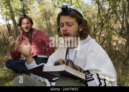 Uman,Ucraina - 02 ottobre 2016. Ortodossi Hasidim Bretslov ebrei pregando la preghiera mattutina nel bosco con gioia, avvolto in uno scialle rituale. Foto Stock