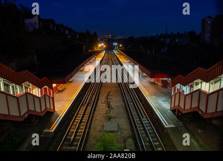 London, England, Regno Unito - 14 Settembre 2019: i passeggeri a piedi lungo le piattaforme a Kensal Green Station nel nord di Londra di notte. Foto Stock