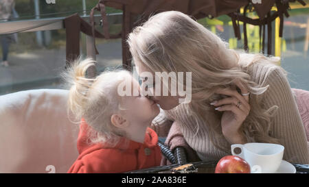 La famiglia in una caffetteria sulla terrazza. Mom gioca con la sua piccola figlia, bacia il Foto Stock
