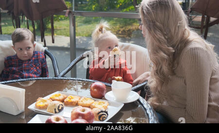 Famiglia nella caffetteria sulla terrazza, piccola figlia alimenta mom con torta Foto Stock