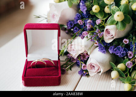 Nozze anelli d'oro e bouquet di fiori sul tavolo bianco Foto Stock