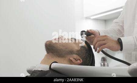 Ritratto uomo asiatico. Le mani di un parrucchiere lavare la testa ai clienti Foto Stock