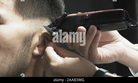 Maschio asiatici parrucchiere tagli capelli clienti in salone Foto Stock