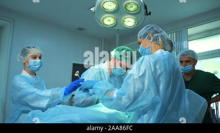 Gruppo di chirurghi al lavoro. Medico infermiere dà una clip utilizzati. Foto Stock
