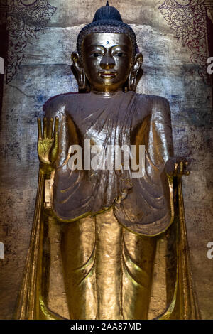 Gautama Buddha, occidente affacciata gold leafed statua di Budda di Tempio di Ananda in Bagan, Myanmar con mani tese che rappresentano fearlessness Foto Stock