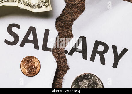 Un foglio di carta con le parole lo stipendio è strappata a metà. Il concetto di crisi finanziaria. Stipendio basso Foto Stock