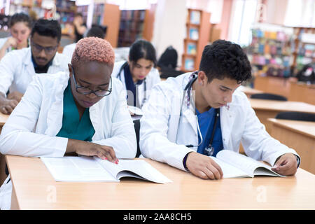 Un gruppo di giovani studenti di medicina con mixed-gara chirurghi esaminando tali operazioni in un computer portatile. Foto Stock