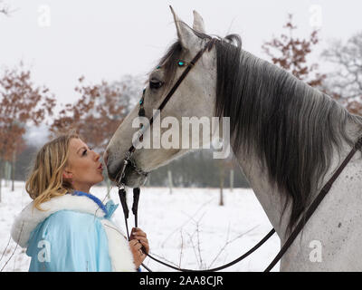 Una magica cercando girl e cavallo in un paesaggio innevato. Foto Stock