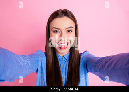 Auto Photo di allegro piuttosto carino dolce bella ragazza tenendo selfie mostrando la sua linguetta isolata influenza su rosa color pastello Foto Stock
