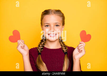 Close-up ritratto di lei bella attraente bella carino dolce Allegro vivace pre-teen ragazza tenendo in mani piccole schede di cuore isolato sul luminoso Foto Stock