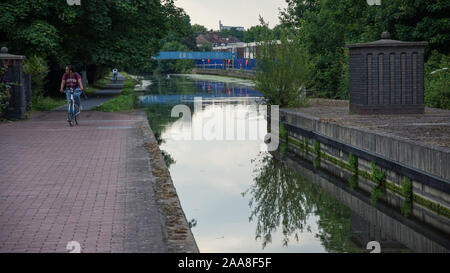 London, England, Regno Unito - 18 Giugno 2017: una donna cicli lungo l'alzaia del Grand Union Canal a Alperton nella zona ovest di Londra. Foto Stock