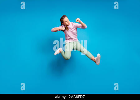 Completa il profilo del corpo foto a lato di concentrato di funky ragazza della gioventù jump treno la sua abilità di combattimento kick gamba nemico indossare abiti moderni maglione isolate su Foto Stock