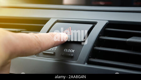 Dito di colpire il pulsante di emergenza in auto .le luci di avvertimento pericolo Foto Stock