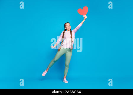 Lunghezza completa di foto sorridente ragazza della gioventù con trecce pigtail tenere la mano catture battenti scheda carta cuore sorpresa su 14-febbraio usura rosa maglione verde Foto Stock