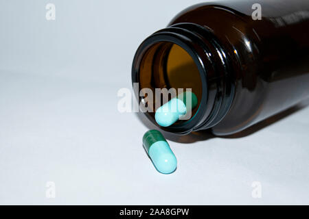Pillola bottiglia versarsi pillole sulla superficie isolata su uno sfondo bianco Foto Stock