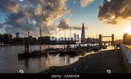 London, England, Regno Unito - 17 Luglio 2015: il sole tramonta oltre l'orizzonte di Londra e barche ormeggiate nel fiume Tamigi vicino al Tower Bridge. Foto Stock