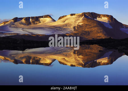 Al mattino presto luce sull'Fannaraken picchi con uno specchio di riflessione come in un lago glaciale, Jotunheim regione, Norvegia Foto Stock