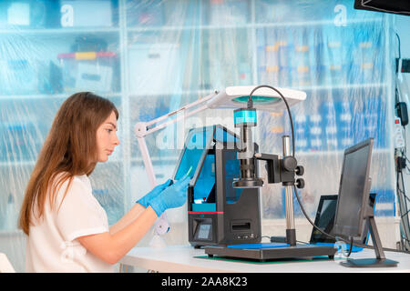 Lavoratore di sesso femminile nel controllo di resina LCD / DLP / SLA stampante 3D nel laboratorio di tecnologia Foto Stock
