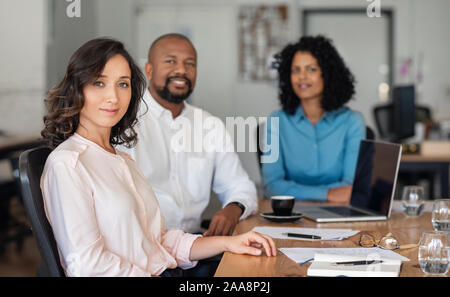 Fiducioso diversi imprenditori seduti insieme ad un tavolo per ufficio Foto Stock